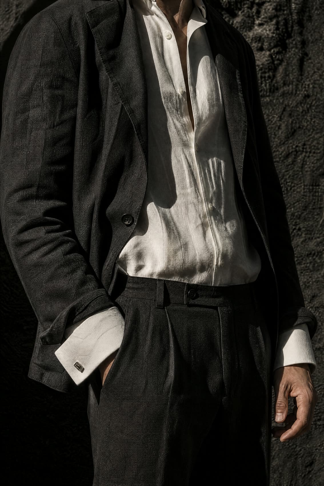 A fine linen shirt with a spread collar and double cuff, worn under an open summer jacket.